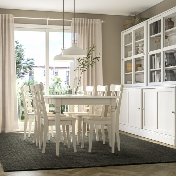 Minimalist dining room with LANDBANA dark green jute rug, complementing chairs and table, emphasising spaciousness.