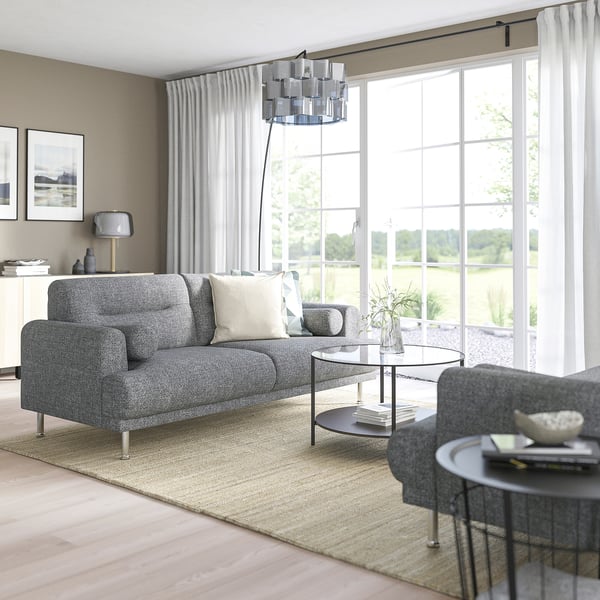 Modern living room with grey LÅNGARYD sofa, glass coffee table, and large window. Sofa is large, comfortable, with a sleek design.