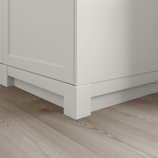 White wooden cabinet base with bevelled edges on light wooden floor.