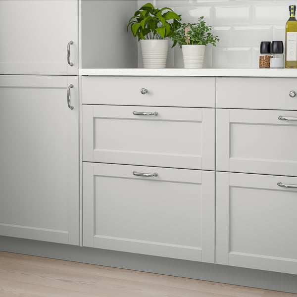 Whites LERHYTTAN kitchen cabinet, light grey with bevelled edges, beside potted plants and glasses.