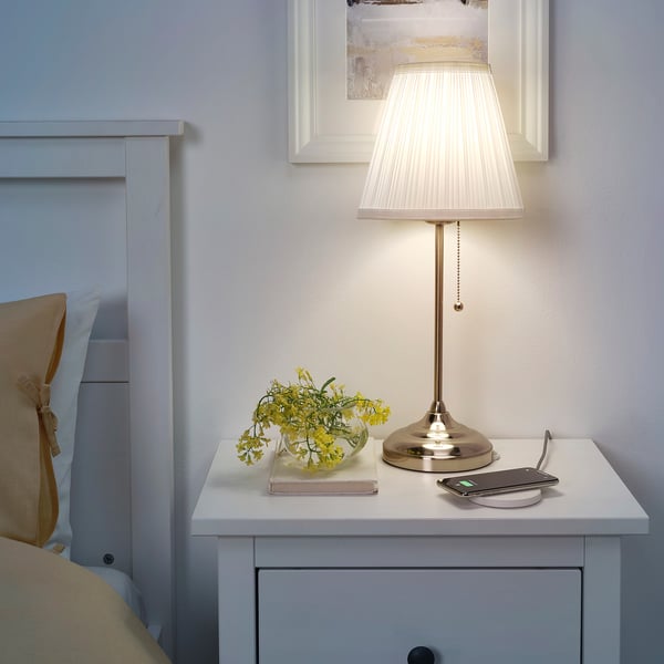 Small bedside table with light, flowers, book, and LIVBOJ wireless charger in white.