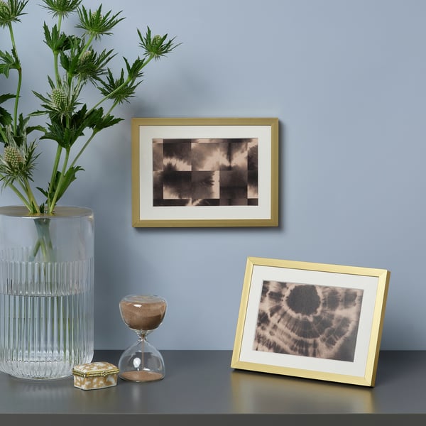 Gold-framed display with two sepia images, plants, and hourglass.