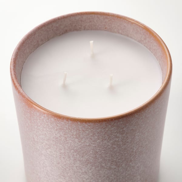 A close-up of a cylindrical, multi-layered glaze candle with three wicks on a white background.