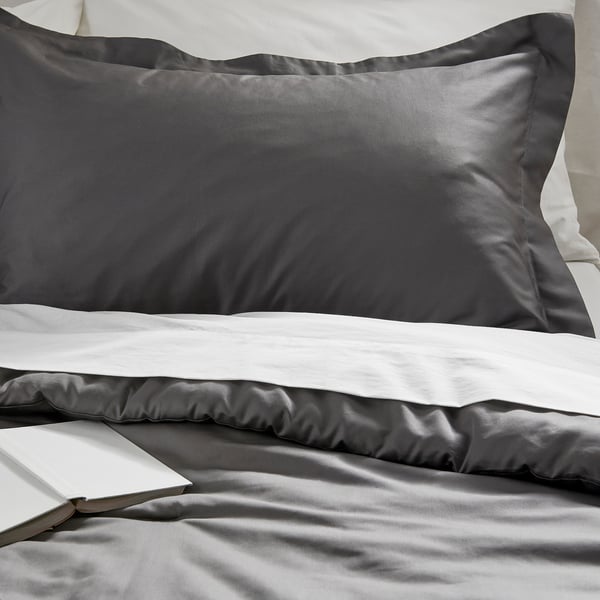 Smooth bedsheet set with shiny finish, neatly folded, and book on top, showcasing luxury and comfort.