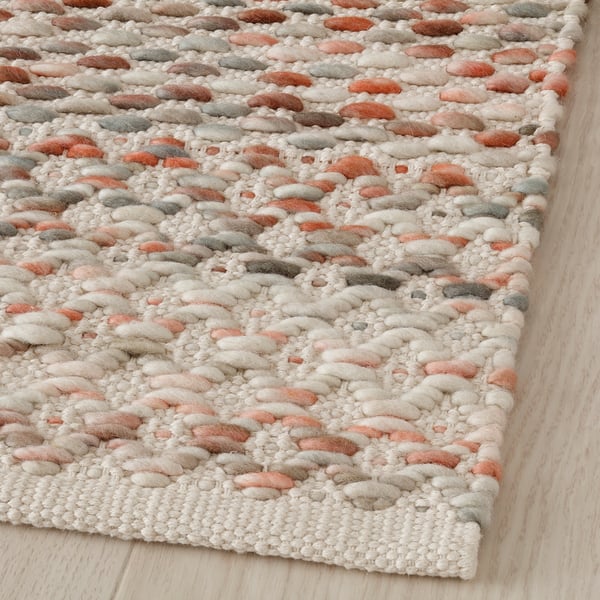 Hand-woven multicoloured rug on wooden floor. Soft wool, intricate patterns, natural design.
