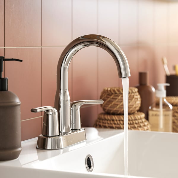 Modern bathroom tap, chrome finish, water flowing.