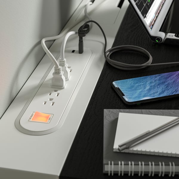 Cable management tray on MITTZON desk with plugged-in devices.