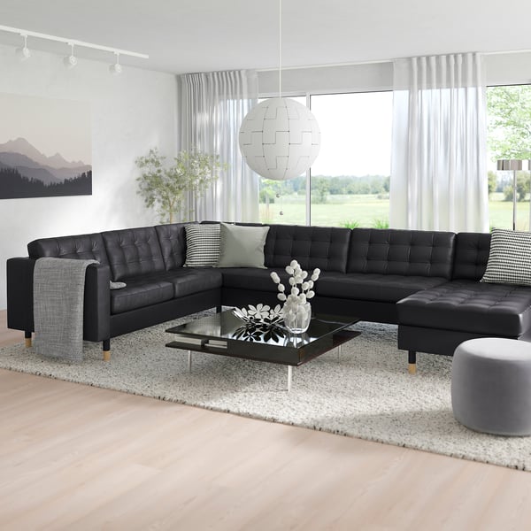 Modern living room: l-shaped sofa, coffee table, rug, window, pendant light, art.
