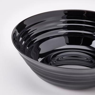 Round black glossy bowl, smooth surface, reflects light, sits on white surface.