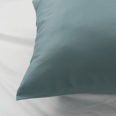 Closeup of a smooth, blue-green pillowcase with a subtle, elegant sheen and wave pattern, showcasing its luxurious texture.