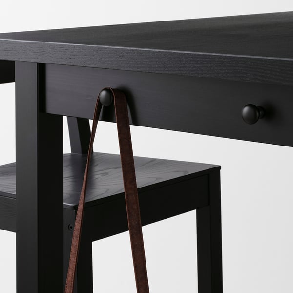 Black bar table with drawer, hooks for storage, suitable for kitchens or dining rooms.