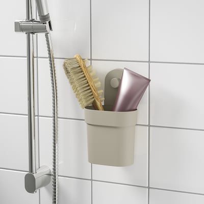 A modern bathroom organiser with a brush and soap holder, attached to tiled wall with suction cups.