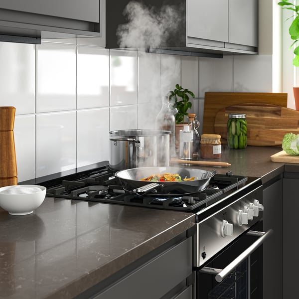 Modern kitchen with sleek stove, pots, and wooden accessories.