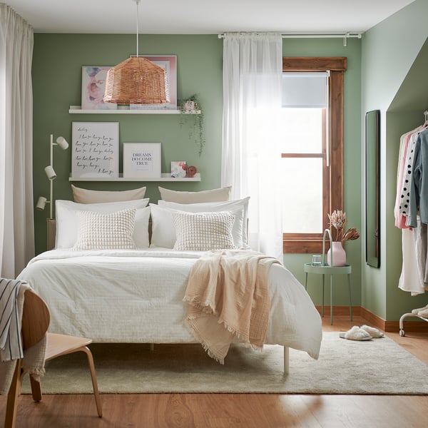 Neutral-toned bedroom with OFELIA VASS bedding, green walls, and wooden accents.
