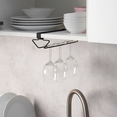 Under-shelf wine glass rack holds three glasses, saving cabinet space. Black metal design securely hangs glasses from shelf.