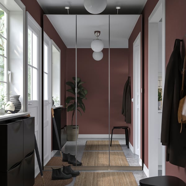 Modern entryway with red walls, white ceiling, and PAX storage system. Includes coats, boots, and a black stool.