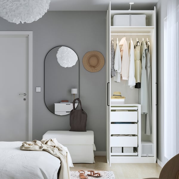 Modern bedroom with open PAX wardrobe showcasing storage and mirror door.