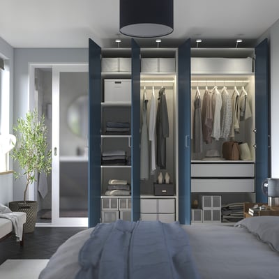 Modern bedroom with open wardrobe showing clothes, accessories, and lighting. Blue doors, shelves, and drawers visible.