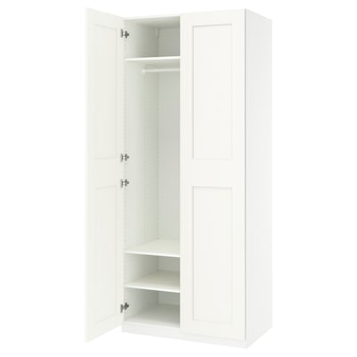 A white IKEA PAX wardrobe with open doors, revealing adjustable shelves and a hanging rod.