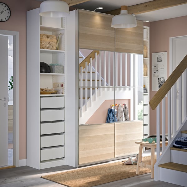 Modern entryway featuring white PAX wardrobe with drawers and shelves, wooden accents, and staircase.