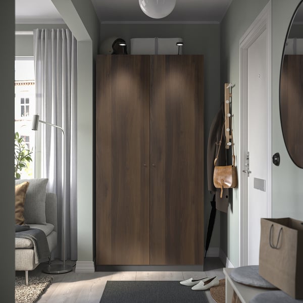PAX: modern, tall wooden wardrobe, standing near white door, tall, dark brown.