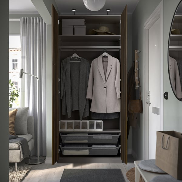 Open wardrobe displaying clothes, with shelves and drawers, set beside entrance door.