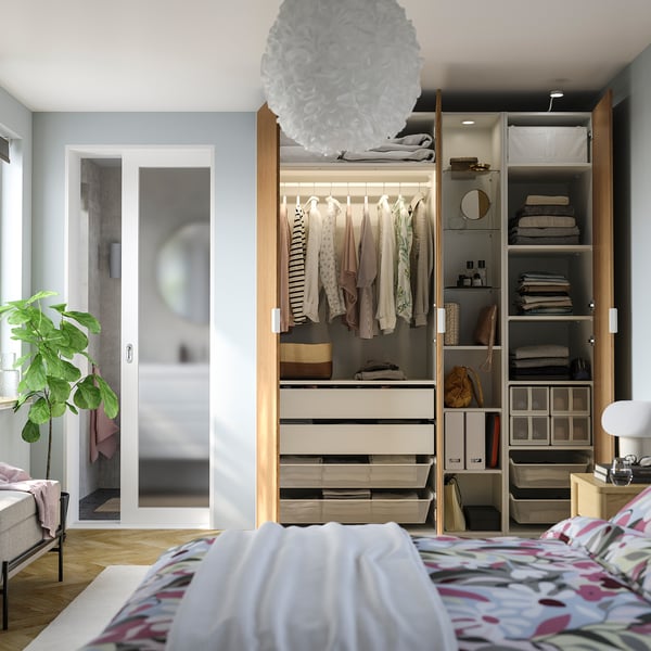 Modern bedroom with open wardrobe, colourful bedding, and large plant.