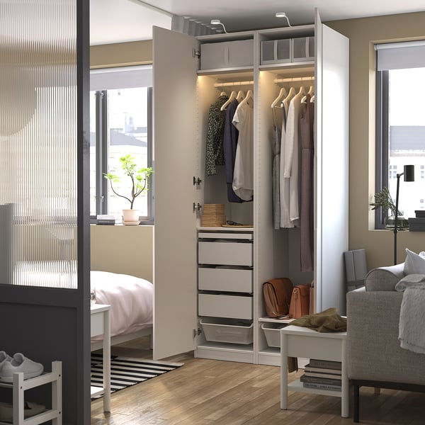 Modern bedroom with open closet displaying clothes and drawers, visible hangers, and interior lighting.