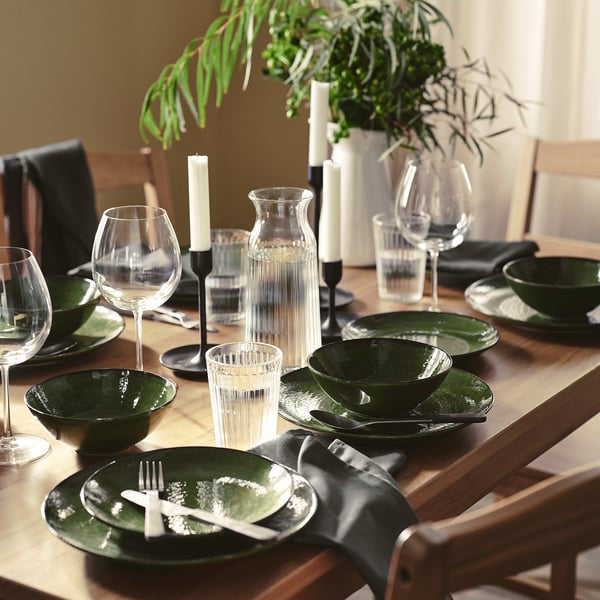 Dark green PELARKAKTUS table setting with dishes, greenery, and candles.