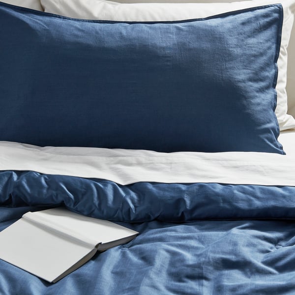 Made bed with blue sham, book, cosy.