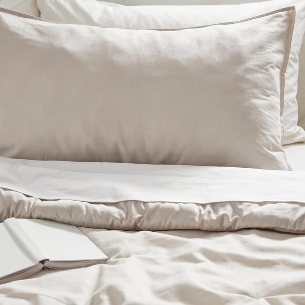 Bed with luxurious, textured beige pillows and a smooth, inviting comforter. Simple, elegant design.