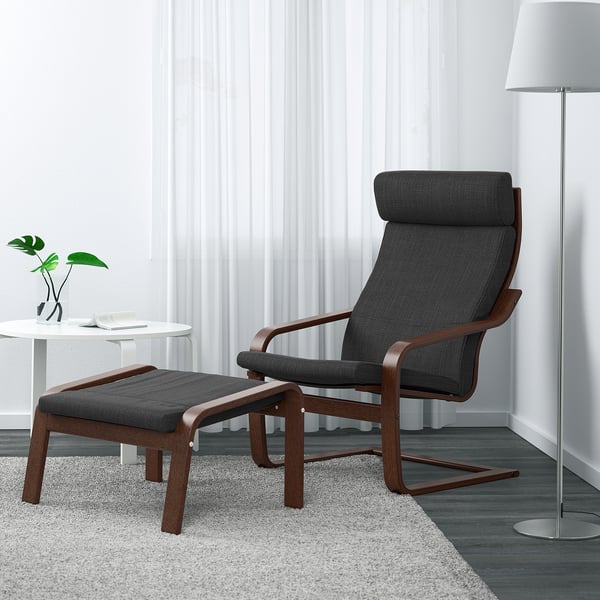 Dark grey POÄNG armchair & stool, wood frame, reclining, in modern room with lamp & plant. Armchair is large, matches white curtain height.
