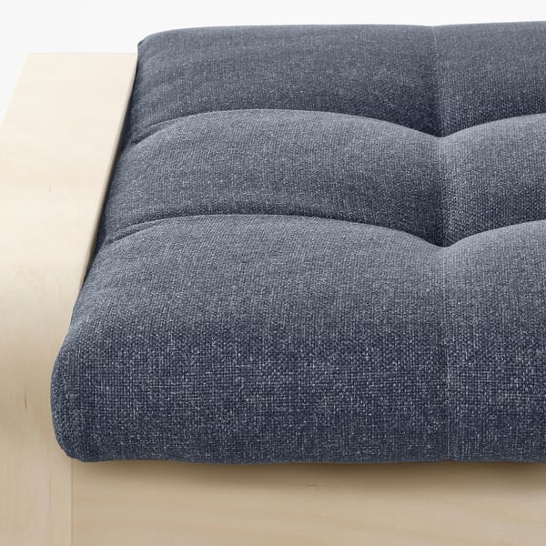Close-up of cushioned footstool showcasing layered fabric design and sturdy wooden frame.