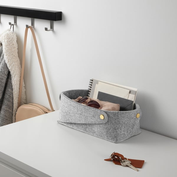 Grey felt basket on desk with sunglasses, papers, keychain, purse, coat.