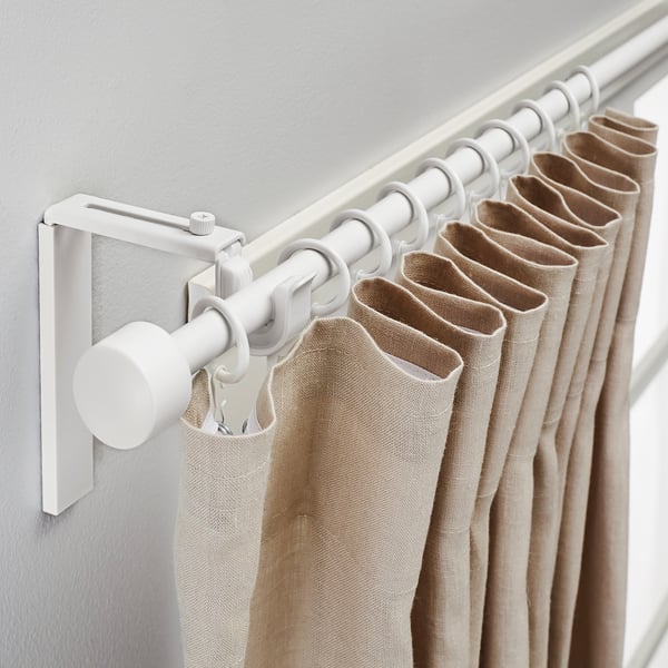 White curtain rod with adjustable length and angle, holding beige curtains.