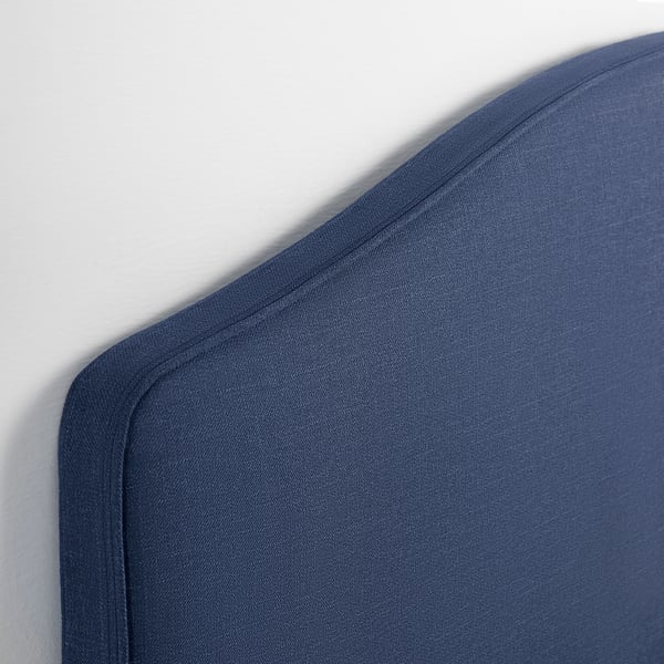 Dark blue upholstered bed frame corner, showing quality stitching and soft fabric.