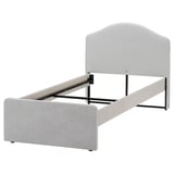 A RAMNEFJÄLL bed in grey. It a simple design with a low headboard and upholstered sides. The structure is made of steel and plywood.