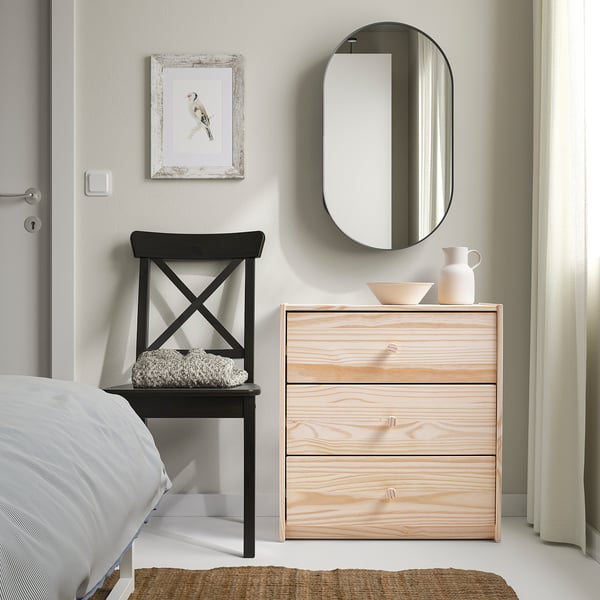 Minimalist bedroom with RAST chest, chair, and mirror. Neutral tones.