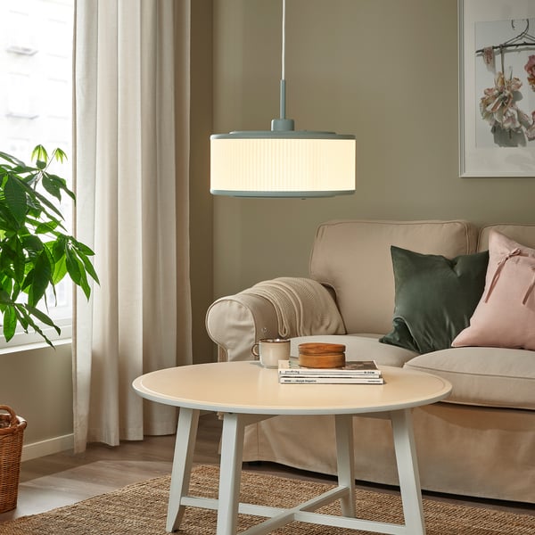 Cosy living room with REMTÅNG pendant lamp over coffee table, casting warm glow.