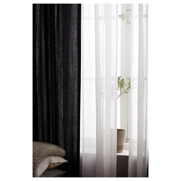 Black RITVA curtains, made of 100% cotton, hang beside sheer whites; knitted pillow visible.
