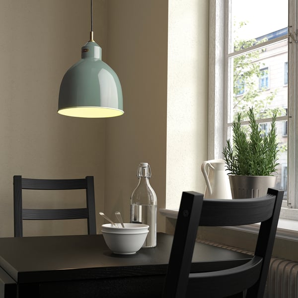 Teal RÖDFLIK lamp over dining table with bowls and plant, warming minimalist decor.