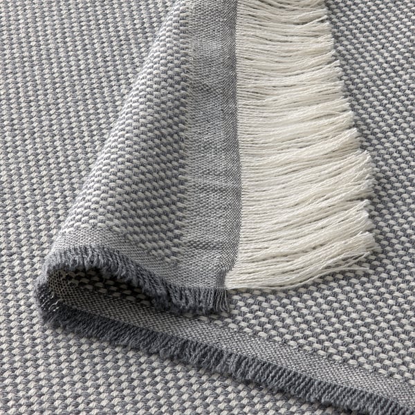 Soft, folded grey throw with fringe, showing textured weave and high quality material.