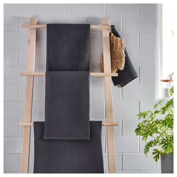 Dark grey SALVIKEN towels on wooden rack. Waffle and terry texture, soft cotton.