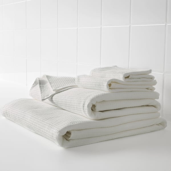 Stacked white towels, soft and absorbent. Waffle texture on one side, plush terry on the other.