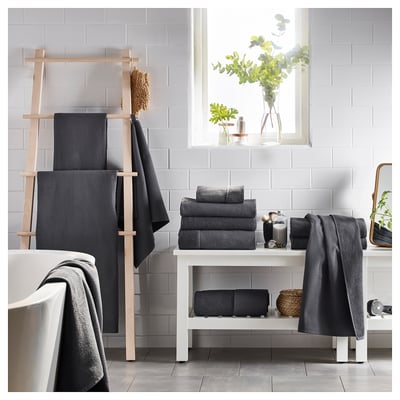 Modern bathroom dark grey SALVIKEN towels on a wooden ladder and white shelf, with a window and plants.