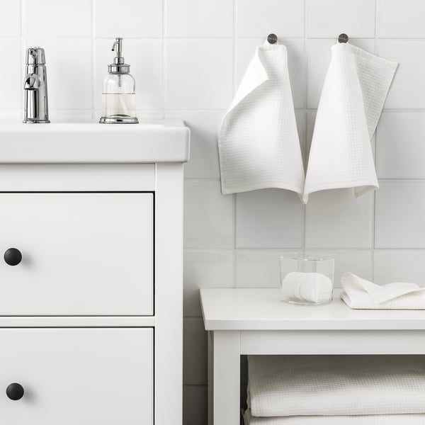 Modern bathroom with white decor, towels, and glass soap dispenser.