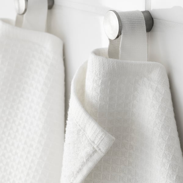 White towel hangers with soft, textured towels. One side is waffle-patterned; the other is terry. Mounted on a sleek, metallic holder.