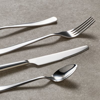 Polished stainless steel cutlery set, including fork, knife, and spoon, arranged neatly on a flat surface, reflecting light for a sleek look.