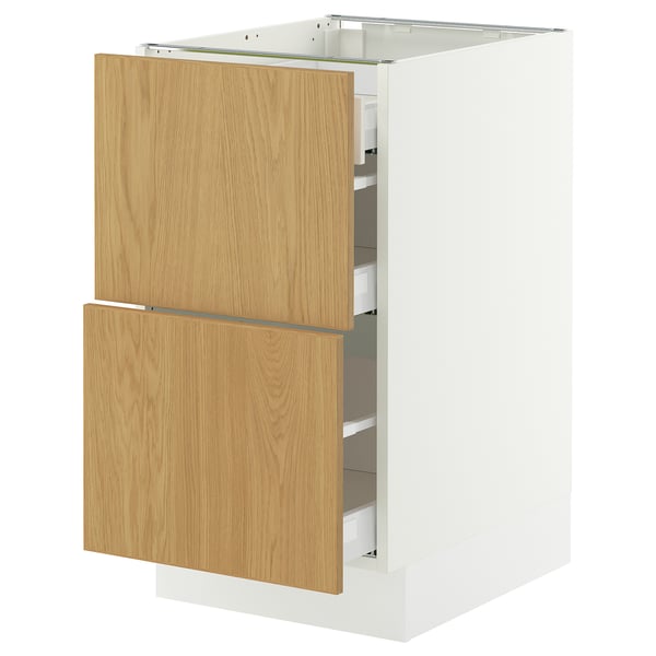 An IKEA SEKTION kitchen cabinet with oak veneer sinarp drawers. Its white with wooden handles, rectangular, and has two open drawers.