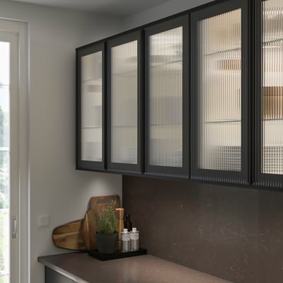 Modern kitchen featuring sleek black SEKTION cabinets with textured glass doors, larger than counter items like cutting board and plants.
